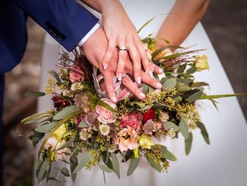 Midsection of bridegroom holding flower bouquet standing outdoors