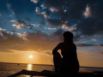 Silhouette man standing at beach against sky during sunset