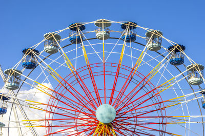 Low angle view of ferris wheel against clear blue sky