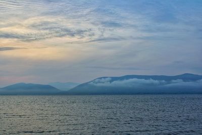 Scenic view of sea and mountains against sky