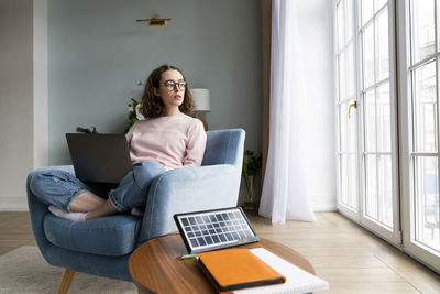 Young freelancer with laptop sitting at home