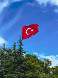 Low angle view of red flag against blue sky