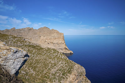 Scenic view of seascape by cliff against clear blue sky during sunny day