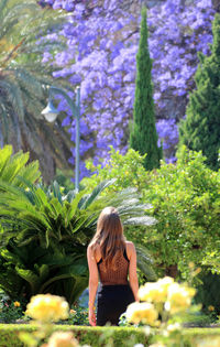 Rear view of woman standing against plants