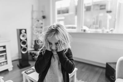 Smiling girl with head in hands standing at home