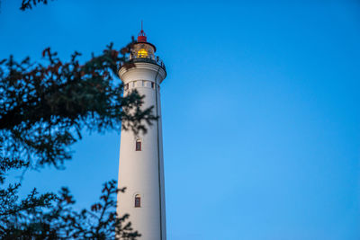 Low angle view of lighthouse by building against sky