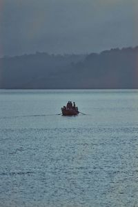 People on boat in sea against sky