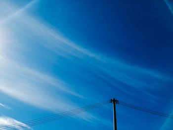 Low angle view of electricity pylon against blue sky