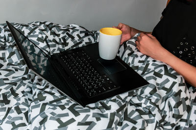 Midsection of man holding coffee cup on table