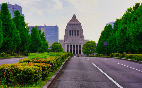 Road passing through city against sky