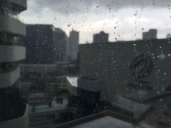 City seen through wet glass window during rainy season