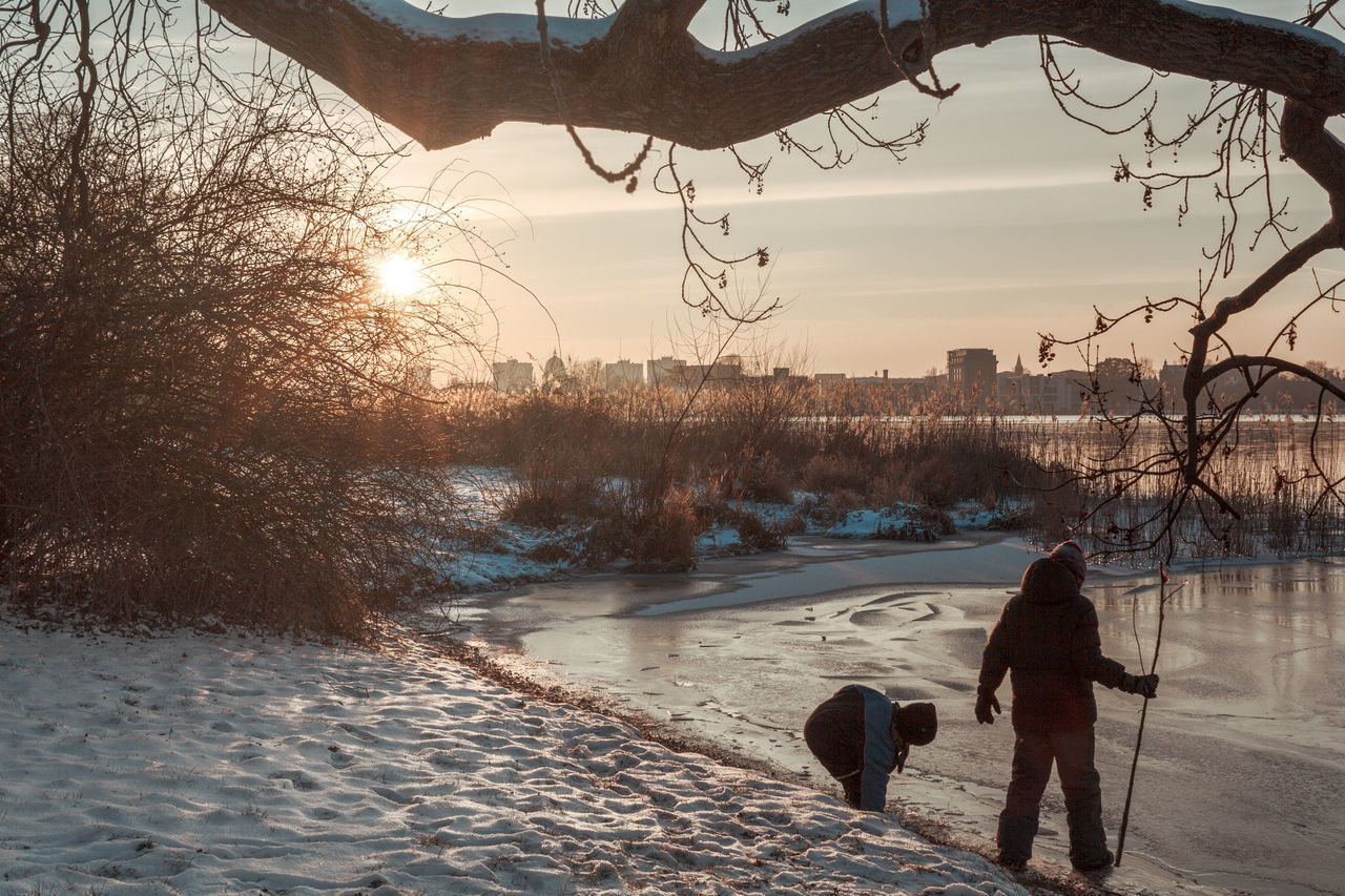 REAR VIEW OF WOMAN WALKING WITH DOG IN WINTER