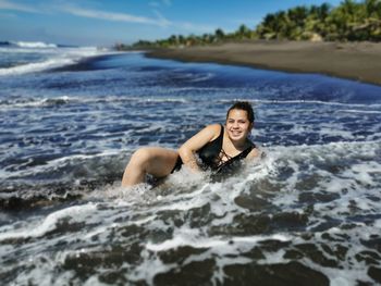 Portrait of young woman swimming in sea against sky