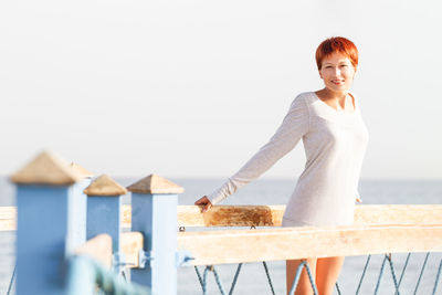 Portrait of smiling woman standing against sky