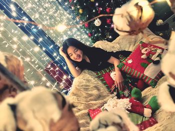 Smiling young woman sitting on bed against christmas decorations at home