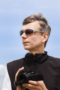 Portrait of man photographing against sky