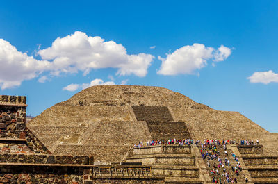 Tourists at pyramid of the sun against blue sky