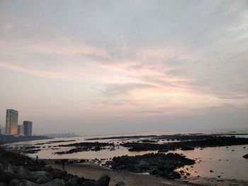 Scenic view of sea and buildings against sky during sunset