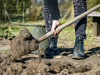 Low section of man digging soil with shovel