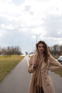 Portrait of a beautiful young woman standing against sky