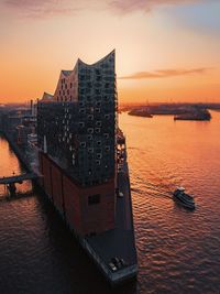 Buildings by sea against sky during sunset