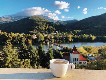 Glass of building by lake against mountains