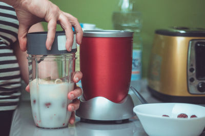 Midsection of woman preparing drink on table in kitchen