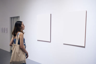 Side view of young woman looking at wall in museum