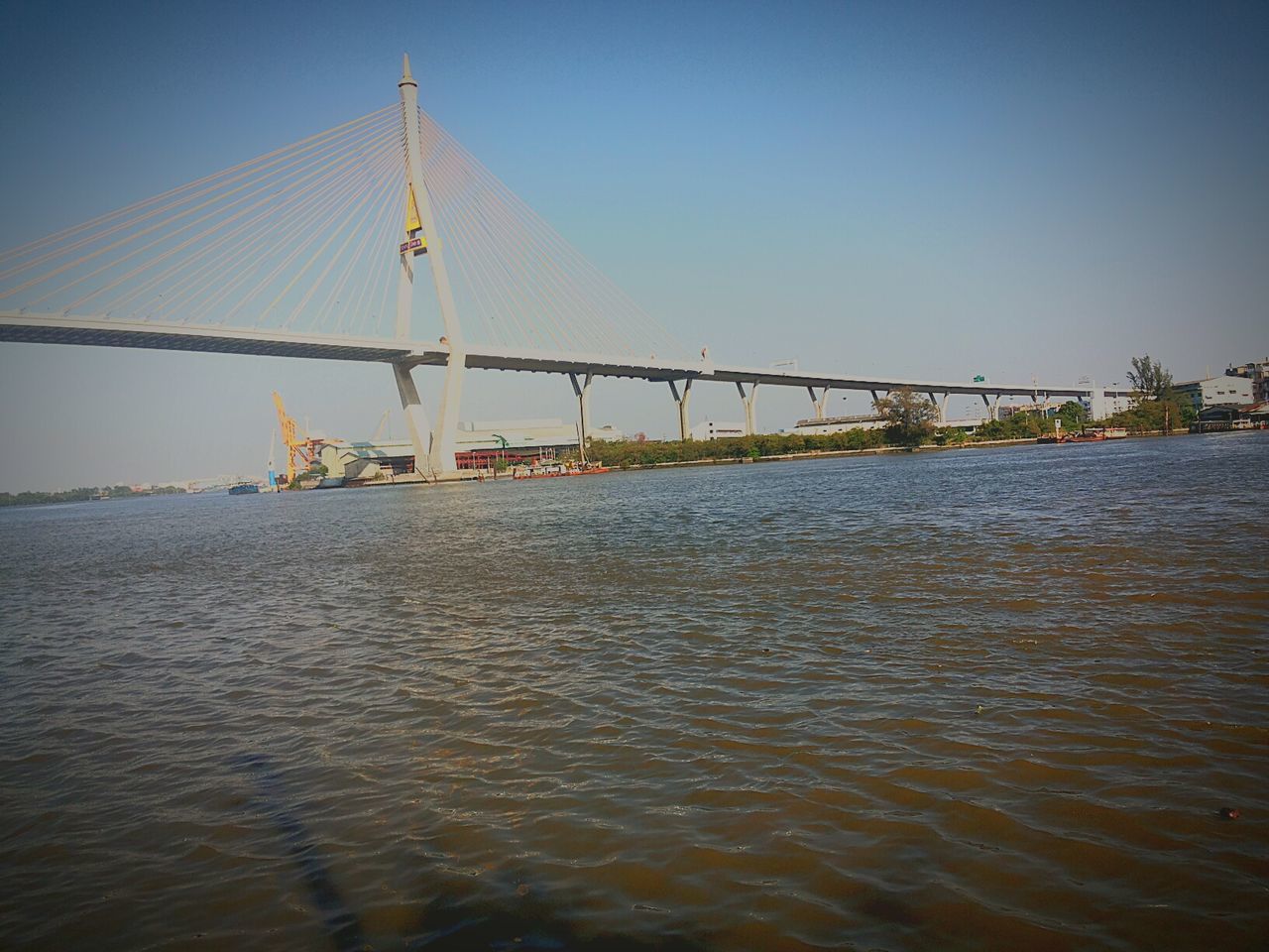water, sea, waterfront, clear sky, built structure, transportation, architecture, nautical vessel, rippled, blue, river, connection, copy space, bridge - man made structure, sky, suspension bridge, nature, tranquility, outdoors, boat