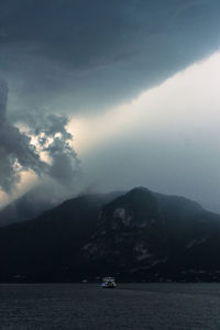 Scenic view of sea by mountains against sky