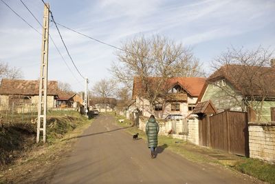 Rear view of woman walking on road against sky