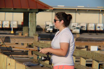 Woman listening music while holding fishing rod in city