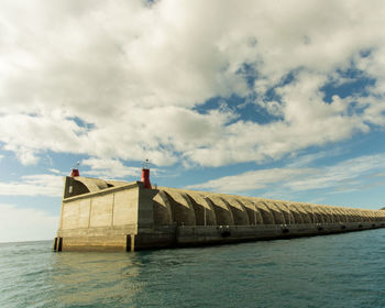 Built structure by sea against sky