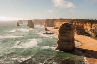 Scenic view of cliff by sea against sky