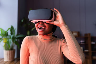 Young excited black woman in vr headset playing action video games with realistic graphics at home