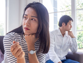 Young couple looking away while sitting on window