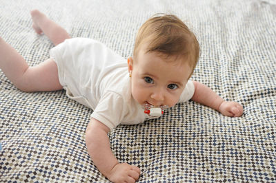 Portrait of cute baby girl lying bed at home