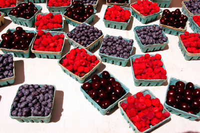 High angle view of various berries in containers for sale at market stall