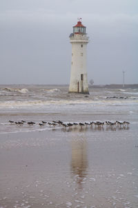 Lighthouse by sea against sky