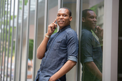 Portrait of a smiling young man standing by window