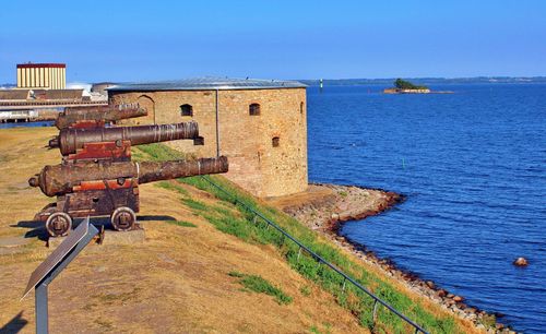 Old ruin by sea against clear blue sky