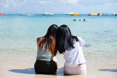 Rear view of women sitting on beach