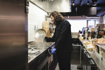 Side view of young male waiter preparing food at restaurant