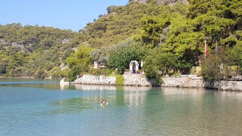 Man swimming in lake against trees and mountains