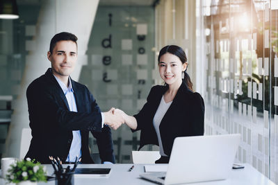 Businesswoman using laptop while standing in office