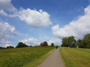 Panoramic view of road amidst field against sky