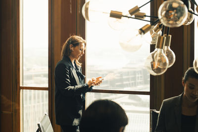 Female lawyer talking through bluetooth on smartphone on board room at law office