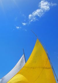 Low angle view of yellow umbrella against blue sky