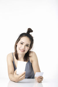 Portrait of smiling young woman using phone against white background