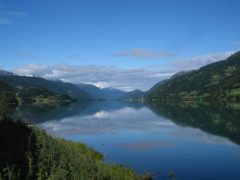 Scenic view of lake and mountains against blue sky